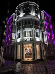 a man sitting in front of a hotel with purple lights at Orient Grand in Tashkent