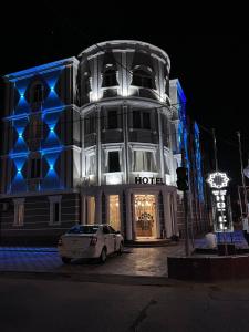 un'auto bianca parcheggiata di fronte a un edificio con luci blu di Orient Grand a Tashkent