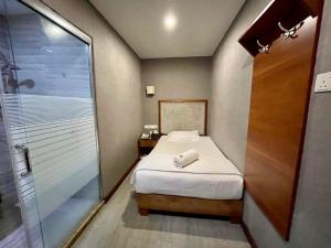 a small bedroom with a bed and a shower at Fan Holiday Hotel in Kuala Lumpur