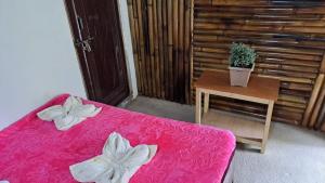 Habitación con cama rosa y mesa con planta en Kasturi Farmstay by StayApart, en Bijanbāri Bāzār