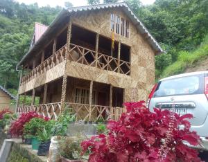 a house under construction with flowers in front of it at Kasturi Farmstay by StayApart in Bijanbāri Bāzār