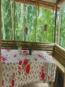 einen Tisch mit einem roten und weißen Tischtuch auf einer Veranda in der Unterkunft Kasturi Farmstay by StayApart in Bijanbāri Bāzār