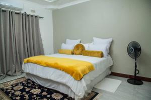 a bedroom with a large bed with a yellow blanket at Netflix/WI-FI, 3 bedroom and free parking in Livingstone
