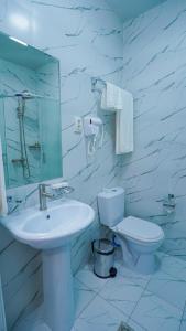 Un baño blanco con lavabo e inodoro. en Almalyk Plaza Hotel, en Olmaliq