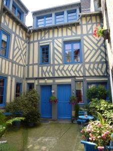 une maison ancienne avec des portes bleues et des fleurs dans l'établissement Reglisse et Pain d'Epices - Chambres d'hôtes, à Honfleur