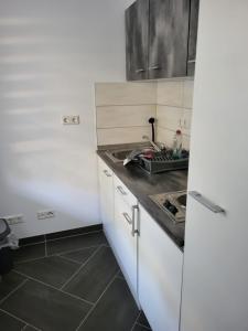 a kitchen with white cabinets and a sink at Gästewohnung 1 in Oschersleben