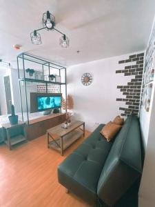 a living room with a green couch and a table at Black & Bold - 1BR Condo 50mbpsWIFI near SM Marilao in Marilao