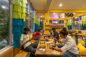 a group of people sitting at a table eating food at The Hosteller Kasol, Riverside in Kasol