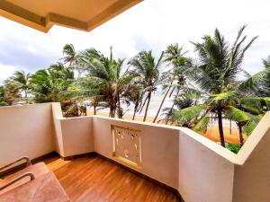 een balkon met uitzicht op het strand en de palmbomen bij Hotel Coconut Bay in Kalutara