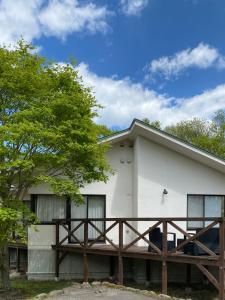 Una casa blanca con un árbol delante. en スイートヴィラパノーラ八ヶ岳, en Kunizakai