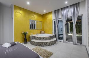 a bathroom with a tub in a room with yellow walls at Villa Martinis in Rogoznica +28 photos