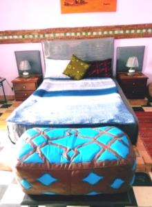 een slaapkamer met een bed met een blauw dekbed bij Dar Sam - Purple Room in Rabat