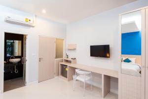 a bedroom with a desk and a bed and a tv at Jinda Resort in Nai Yang Beach