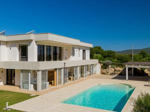 une grande maison blanche avec une piscine en face de celle-ci dans l'établissement Villa Green - Sardegna, à Calangianus
