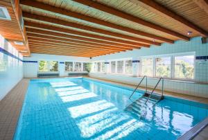 a large swimming pool with blue tiles and windows at Panorama Hotel Winterberg in Winterberg