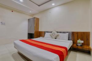 a bedroom with a large white bed with a red blanket at Hotel Kumar Atithi Nivas in Indore
