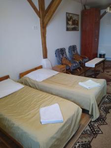 a room with two beds and two chairs in it at Zajazd Eljan-Centrum Noclegowe in Olsztyn