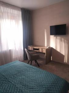 a hotel room with a bed and a desk and a television at Hotel Prydesnyansky in Chernihiv