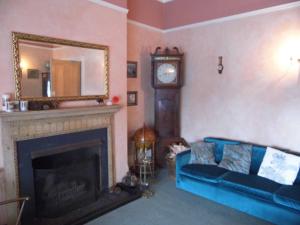 a living room with a blue couch and a clock at The Sandhill in Sandown