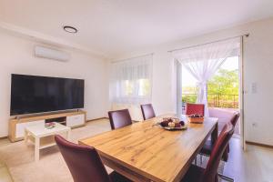 a living room with a wooden table and a television at Mártoni Villa in Szigetszentmárton