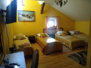 a bedroom with three beds in a room with yellow walls at Zajazd Eljan-Centrum Noclegowe in Olsztyn