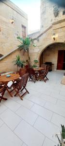 an outdoor patio with wooden tables and chairs at Ta Majsi farmhouse with indoor heated pool in San Lawrenz