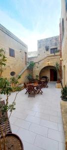 a patio with tables and chairs in a building at Ta Majsi farmhouse with indoor heated pool in San Lawrenz