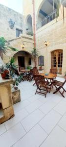 eine Terrasse mit Stühlen, einem Tisch und einem Kamin in der Unterkunft Ta Majsi farmhouse with indoor heated pool in San Lawrenz