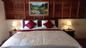 1 dormitorio con 1 cama con almohadas rojas y 2 lámparas en The Hill Prananta, en Polilit
