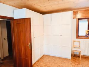 um quarto com paredes brancas e uma porta de madeira em Delizioso appartamento a Canove di Roana em Camporovere