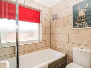 a bathroom with a tub and a toilet and a window at Curlew Cottage in Lymington +37 photos