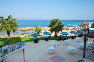 Pola Costa Beach Hotel Apts - Adults Only في بروتاراس: اطلالة على شاطئ به طاولات وكراسي ومظلات