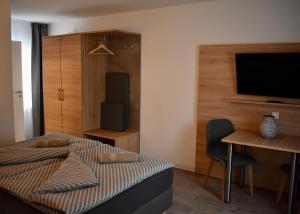 um quarto com uma cama, uma mesa e uma televisão em Kontorhaus Senftenberg em Senftenberg