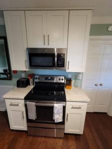 a kitchen with a stove and a microwave at Large Modern Southern Pool Home Near Shops in Memphis