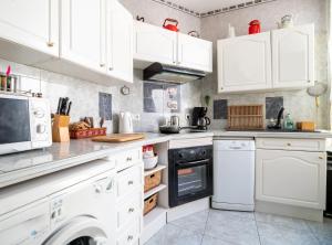 eine weiße Küche mit weißen Schränken und Geräten in der Unterkunft Appartement de 2 chambres avec vue sur la ville et wifi a Saumur in Saumur