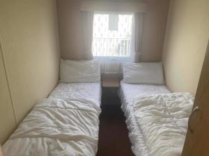 two beds in a small room with a window at 2 bedroom caravan in hunstanton free wi-fi in Hunstanton