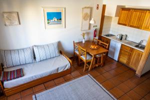 a living room with a couch and a table and a kitchen at Hotel Apartamento Porto Covo in Porto Covo