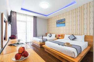 a hotel room with two beds and a table with a bowl of fruit at Dalat Wind Hotel in Da Lat