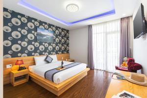 Dalat Wind Hotel في دالات: غرفة نوم بسرير كبير وجدار وصحون