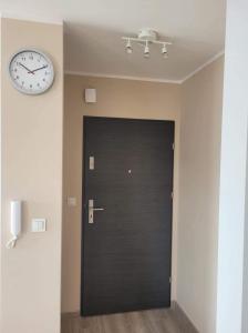 a black door with a clock on a wall at Kawalerka Wałowa 3 in Wejherowo