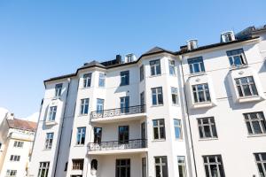 a white apartment building with a blue sky in the background at Frogner House - Uranienborg in Oslo