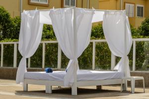 uma cama de dossel com cortinas brancas num banco em Hotel Apartamentos Vibra San Marino em Baía de San Antonio