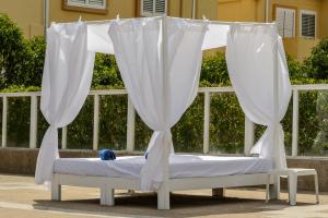 サン・アントニオ・ベイにあるHotel Apartamentos Vibra San Marinoの天蓋付きベッド(ベンチに白いカーテン付)