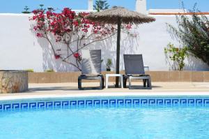 twee stoelen en een parasol naast een zwembad bij Hotel Apartamentos Vibra San Marino in San Antonio Bay
