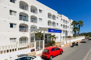 a red car parked in front of a building at Hotel Apartamentos Vibra San Marino in San Antonio Bay