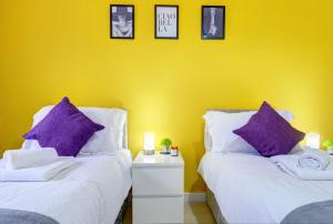 2 Betten mit lila Kissen in einem gelben Zimmer in der Unterkunft Honeysuckle Road in Sheffield