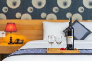 a bottle of wine and two glasses on a bed at Dalat Wind Hotel in Da Lat