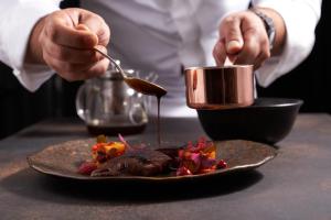 una persona sosteniendo una taza sobre un plato de comida en Logis Hôtel - Restaurant Maison Claude Darroze en Langon