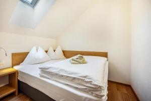 a bedroom with a bed with white sheets at App Kronplatz Villa Colli in Valdaora