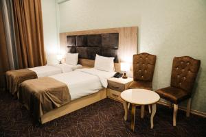een hotelkamer met 2 bedden en een stoel bij The Clocktower Hotel in Baku